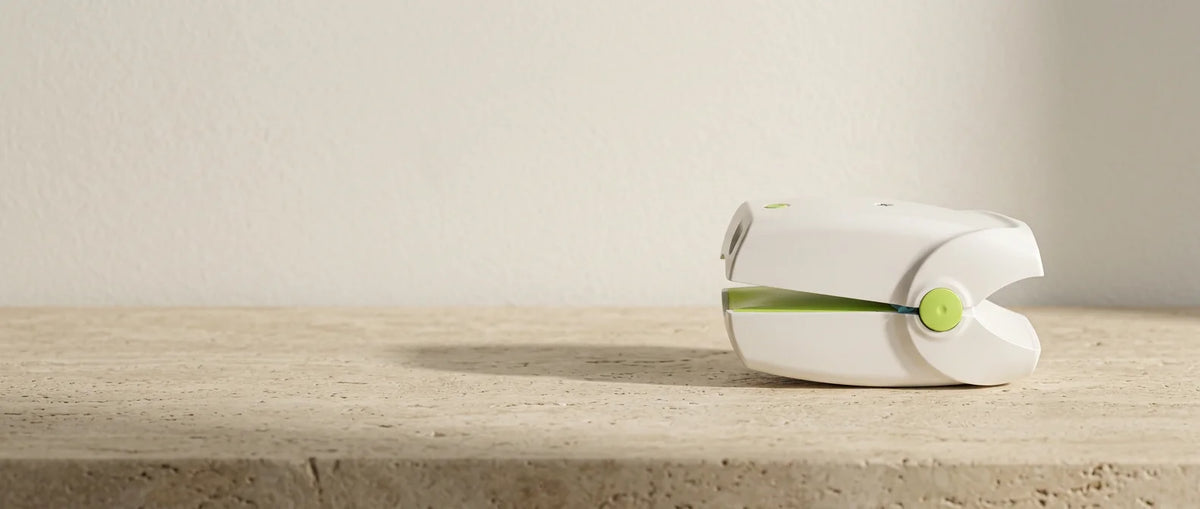 The device on a warm stone surface beside a sprig of eucalyptus
