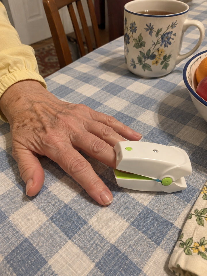 AI-created illustration of a NailNova device clipped onto a fingernail at a kitchen counter.